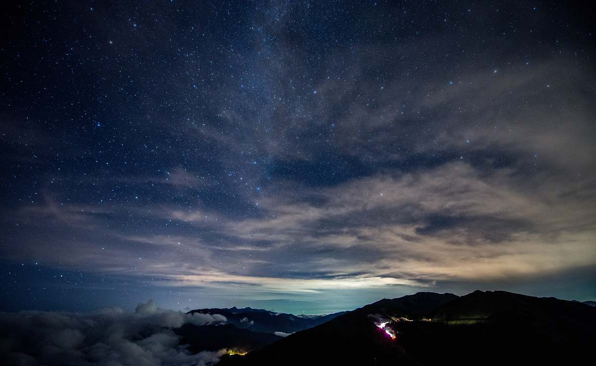 milky way silhouette of mountain under white and gray clouds photo night